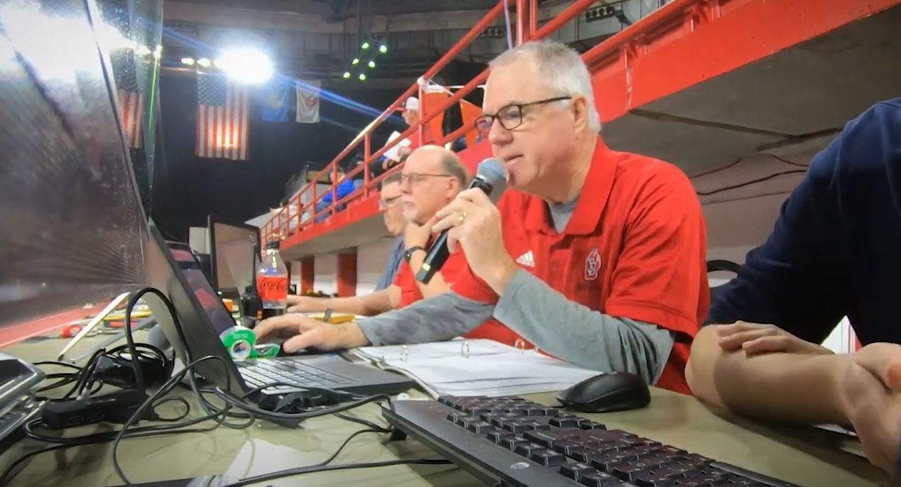 Longtime meet announcer Greg Merrigan calls the action at the 2022 Dan Lennon Invitational in Vermillion.